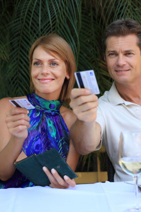 man and woman holding credit cards at a table on a date